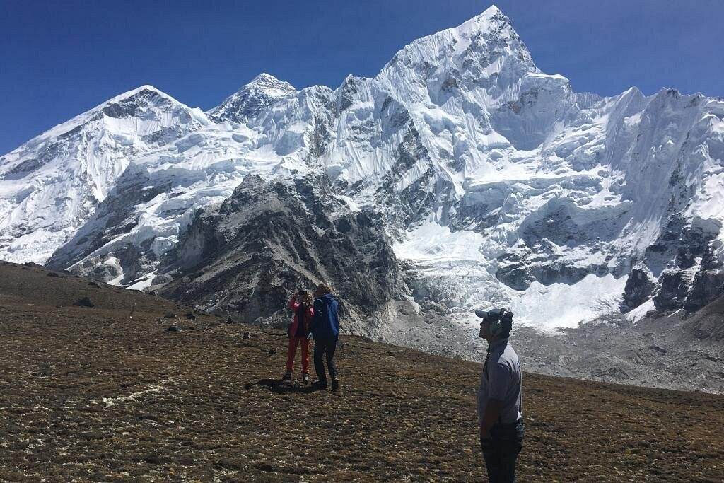 Trekkers admire the majestic Mount Everest under a clear blue sky, embodying luxury mountaineering with premium gear and an exclusive high-altitude adventure