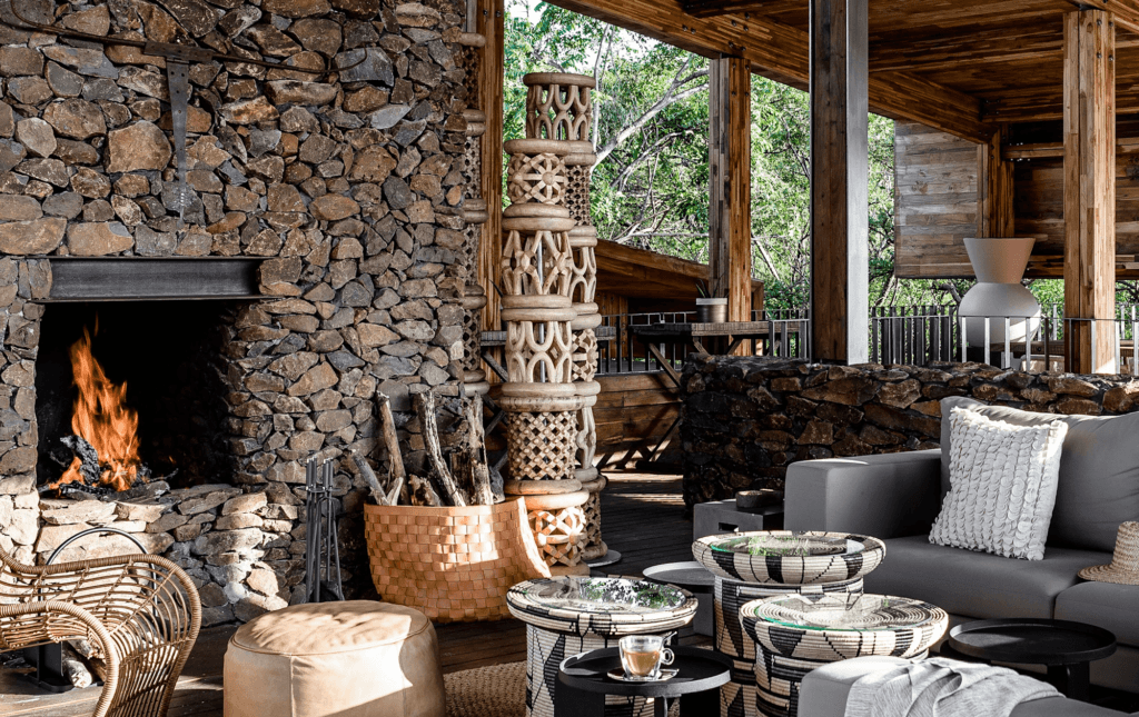 Luxury safari lodge interior at Singita with stone fireplace, African-inspired woven furniture, and open-air design surrounded by nature in the African bush